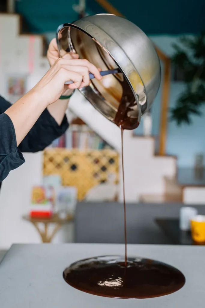 Mains versant du chocolat fondu sur un plan de travail