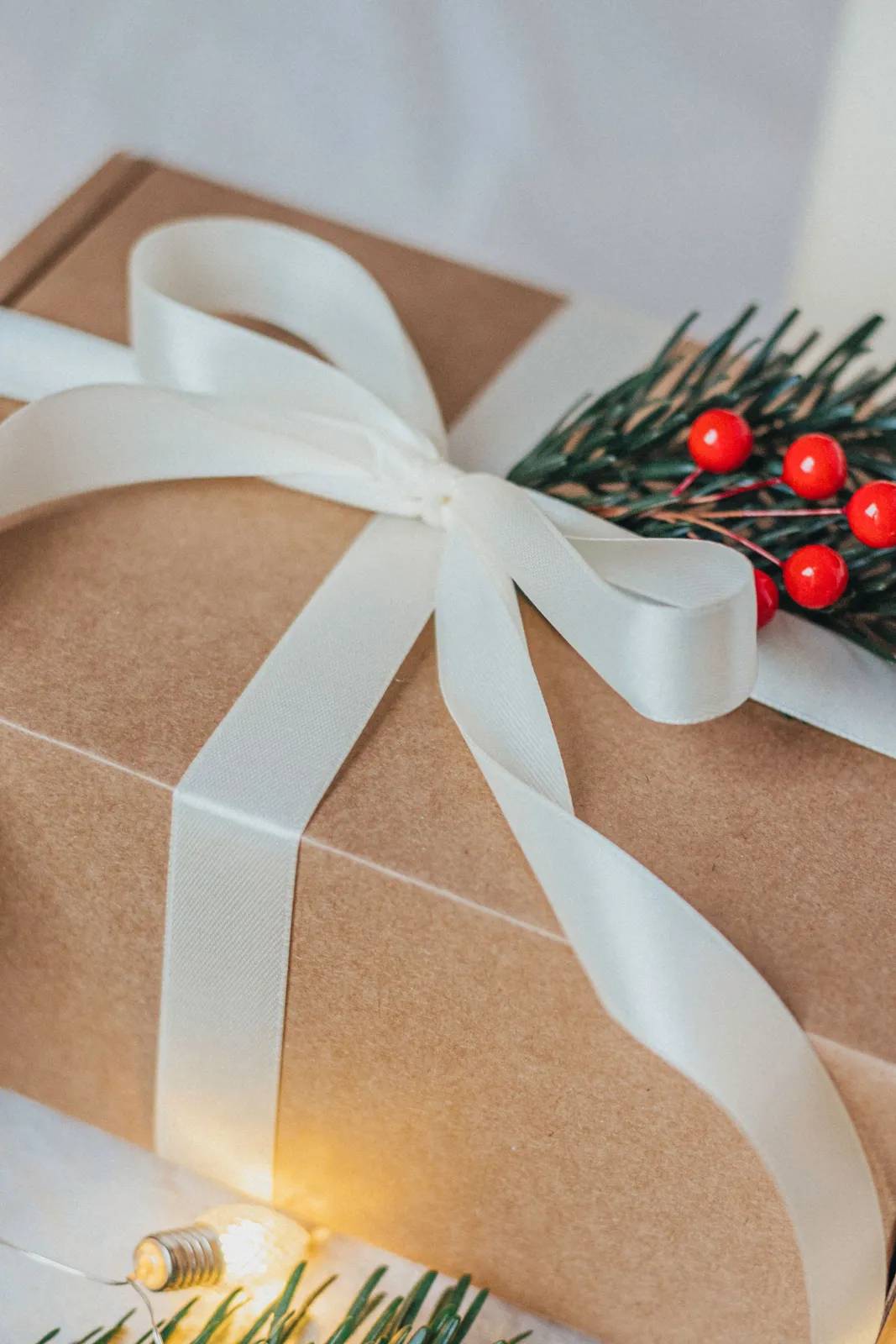 Coffret kraft noué d'un ruban blanc avec une branche de houx