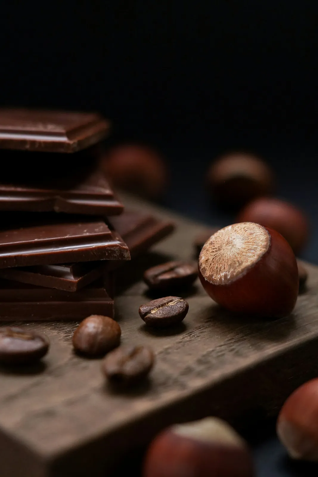 Morceaux de chocolat noir et noisettes sur une table sombre