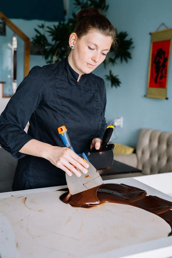 Une chocolatière travaille le chocolat sur le marbre