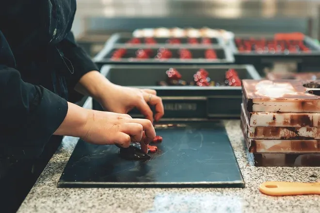 Mains disposant des bonbons de chocolat sur un plan de travail