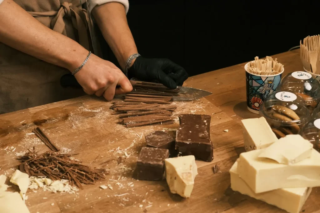Mains en tablier travaillant du chocolat sur une planche en bois